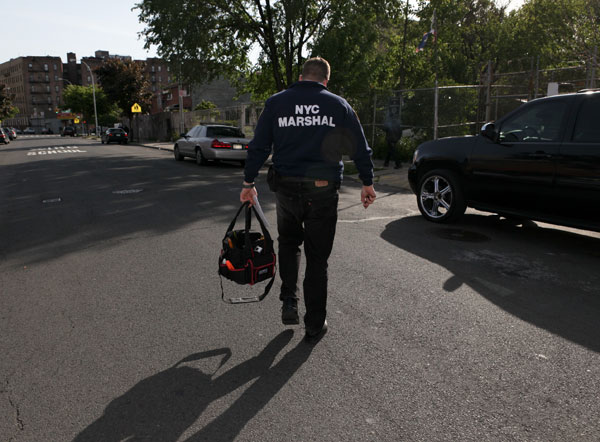 City Marshall Oren Varnai walks back to his car after helping a Con Edison worker seize a gas meter from a delinquent customer in the Bronx. Varnai's application process to become a marshal took three years until he was appointed by the mayor.