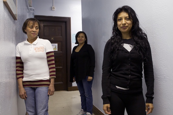 Members of Si Se Puede, a cleaning cooperative, stand behind Yadira Fragoso after a meeting in Sunset Park, Brookly